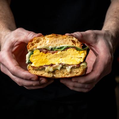 Hands holding the deluxe breakfast sandwich.