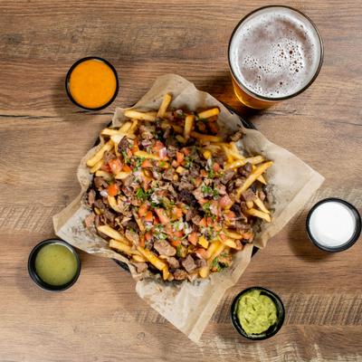 Steak fries served with nacho cheese, guacamole, sour cream, green salsa, and a beer.