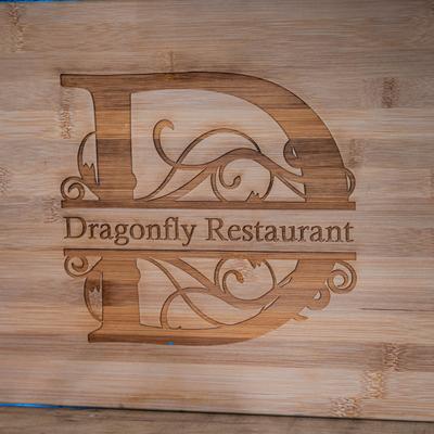 Engraved cutting board with a large decorative D and the words Dragonfly Restaurant.