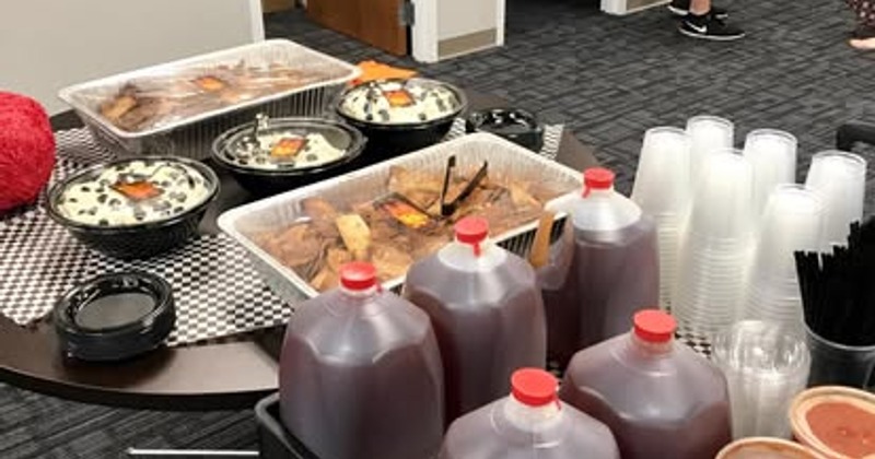 Catering setup featuring gallon beverage jugs and foil catering trays