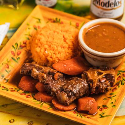 Stewed beef with carrots and sides of rice and beans.