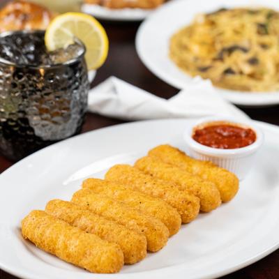 Mozzarella sticks served with marinara sauce, alongside a cocktail and other dishes.
