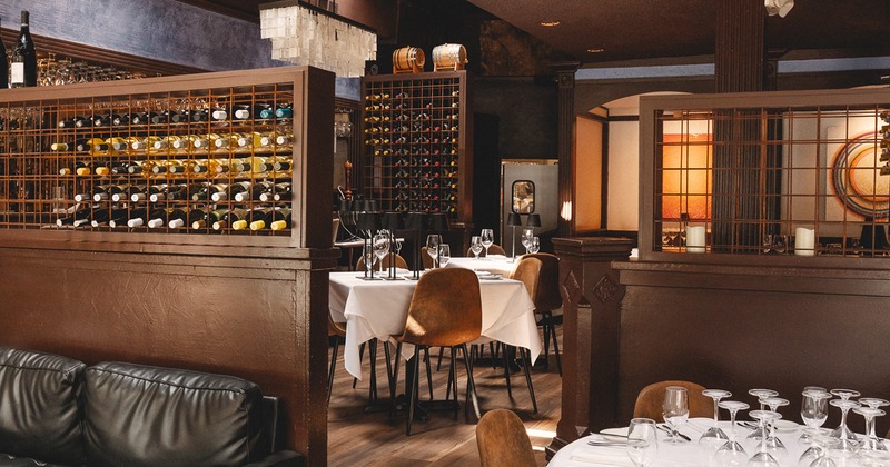 Restaurant interior, cozy dining area with set tables and wine racks