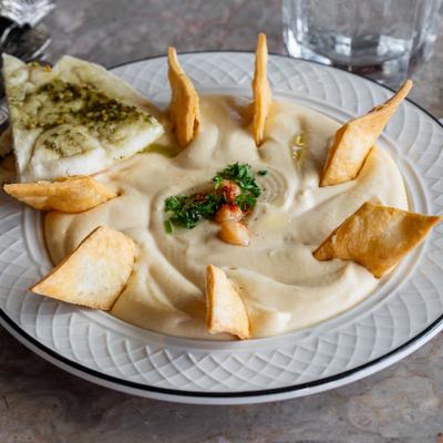 Hummus topped with herbs, served with pita chips and bread.