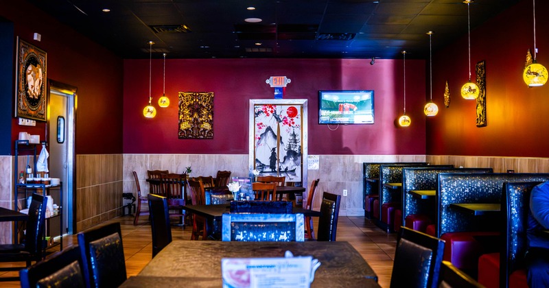 Restaurant interior with red walls, wooden furniture, pendant lights, and decorative art