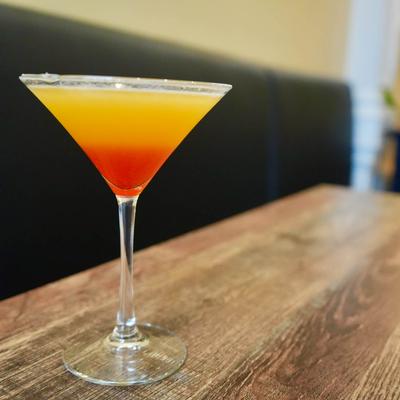 A layered red and orange cocktail in a martini glass.