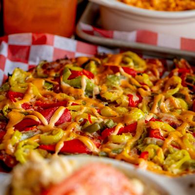 Pizza topped with melted cheese, bell peppers and a drizzle of chipotle mayo.