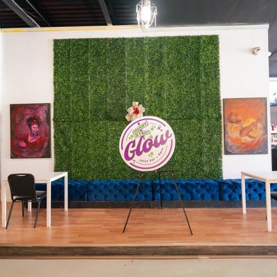 Decorative venue space with vertical garden panel, signage and  blue velvet-tufted bench.