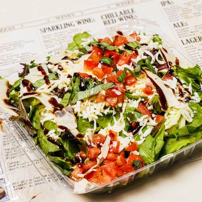 Caprese salad topped with balsamic reduction, fresh basil, and parmesan.