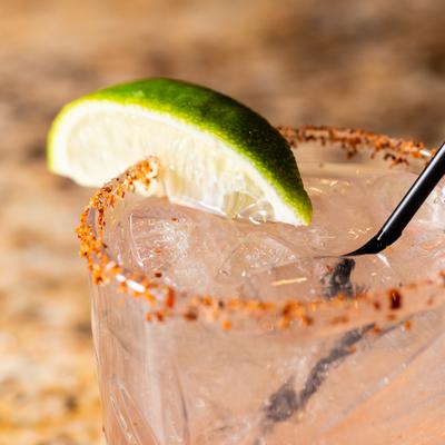 Cocktail drink with spiced rim and lime wedge, close up.