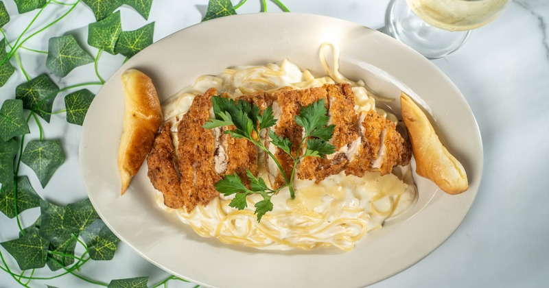 Chicken schnitzel served over pasta with a creamy white sauce