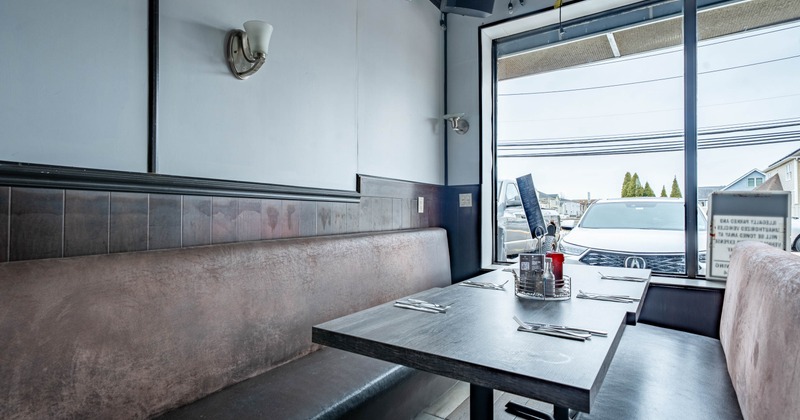 Interior with a booth seating area and a large window showing parked cars outside