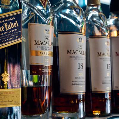 Lined whisky bottles displayed on a shelf.