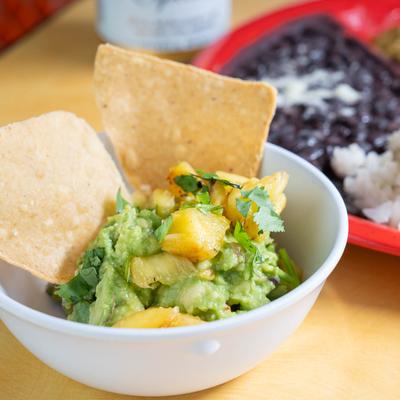 A bowl of guacamole topped with pineapple.