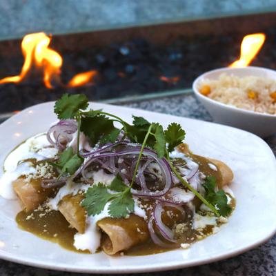 Enchiladas Bien Verdes topped with crema, sliced red onions and cilantro.