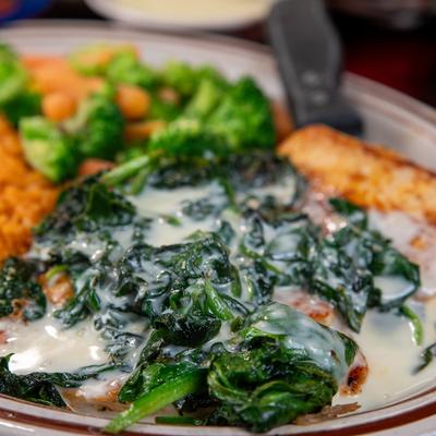 Chicken breast topped with spinach and cheese, served with rice, and veggies.