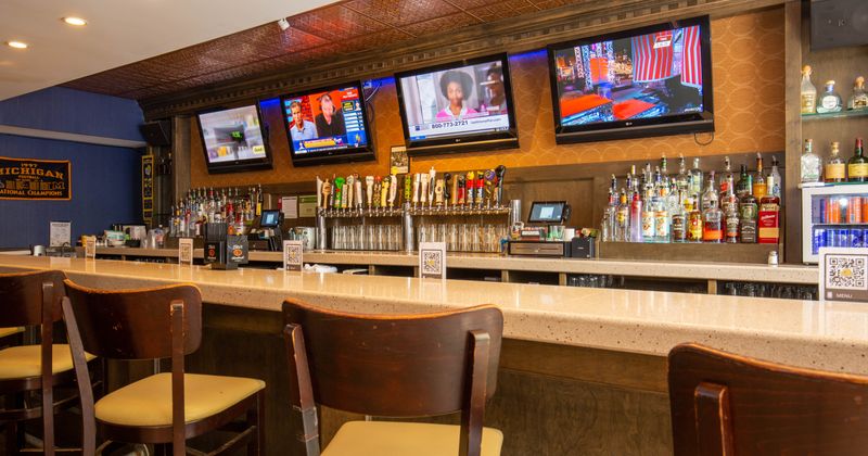Interior, several TVs mounted on wall above bar area
