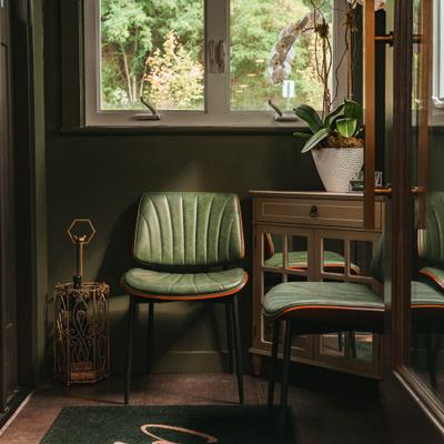 Cozy corner with green velvet chairs and potted plant.