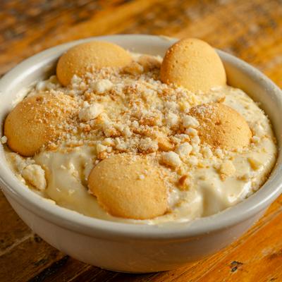 Banana Pudding served in a white bowl on a rustic wooden table.