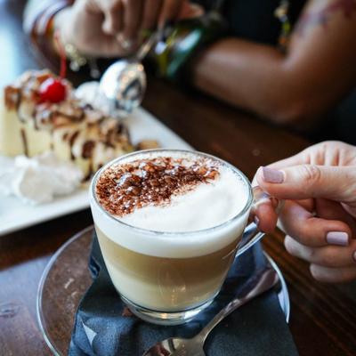 A woman holding a coffee, closeup on the coffee.
