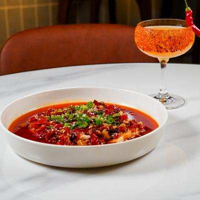 Chilean seabass in spicy red sauce, served alongside spicy cocktail.