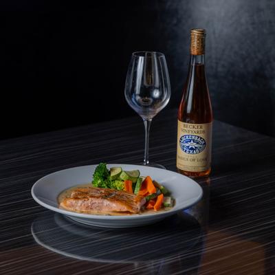 Grilled salmon with steamed vegetables served with wine.