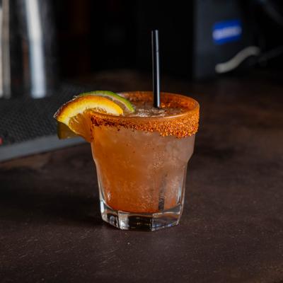 Margarita drink served in a glass with spiced rim, garnished with lime and lemon wedge,.