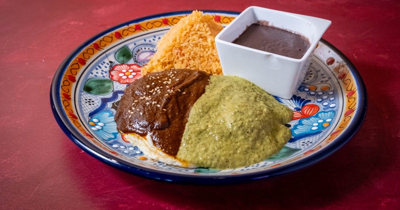 Tortillas topped with sunny side eggs, and red and green sauce