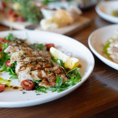 Grilled and sliced chicken with arugula, tomatoes, and lemon, close-up.