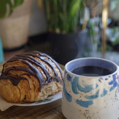 Chocolate croissant served with a cup of black coffee.