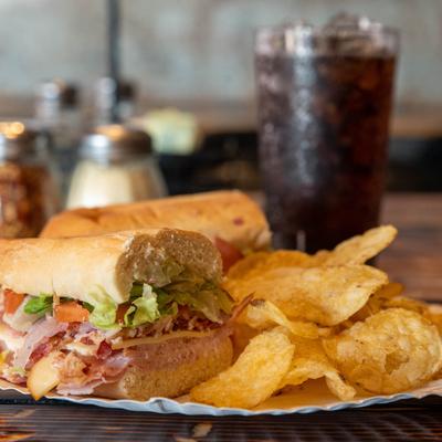 Smokestack sandwich served with potato chips and a soft drink.