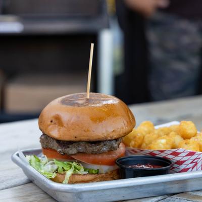 Burger, with lettuce, tomato, onion, and a side of tater tots.