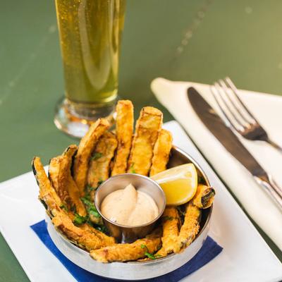 Zucchini Fries on a plate, glass of beer behind.