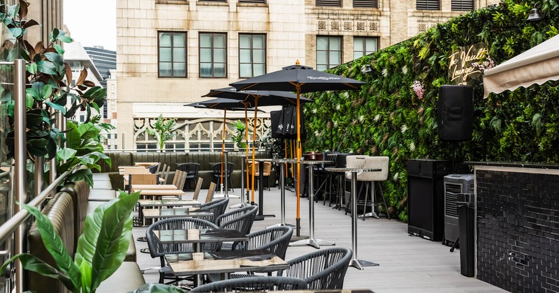 Exterior, terrace, seating area, tables with chairs, artificial green wall, neon signage