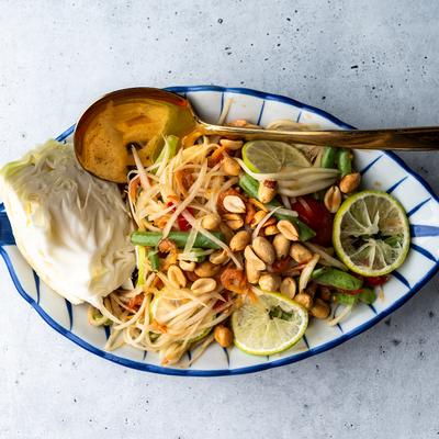 Thai papaya salad with peanuts, green beans, lime, and cabbage.