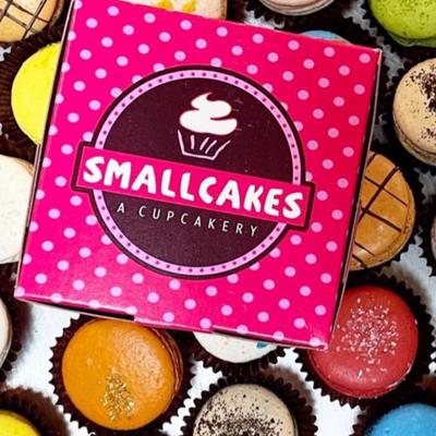 Small Cakes box placed on top of assorted cupcakes.