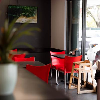 Modern restaurant interior featuring vibrant red chairs and dark tables.