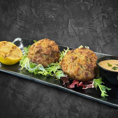 Crab cakes with green salad, lemon, and sauce.