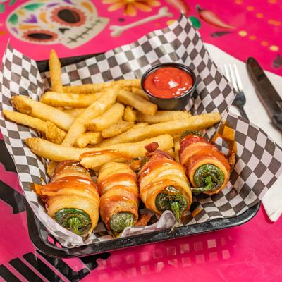 Bacon-wrapped jalapeños stuffed with cheese, served with french fries.