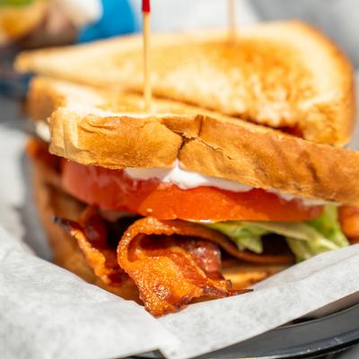 Close-up of a BLT sandwich stacked with bacon, lettuce, and tomato.