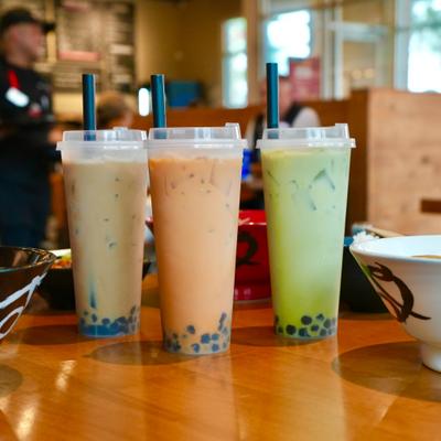 Various cups of Bobs Tea served on the table with assortiment of food.