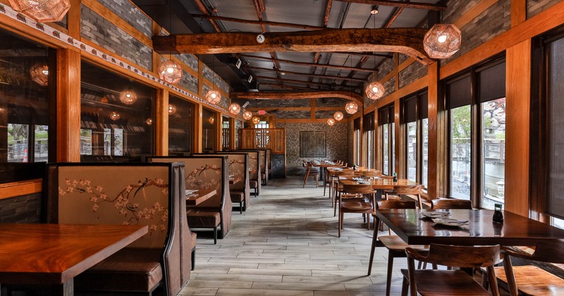 Interior, booth seating, wooden tables and chairs, pendant lighting, and large windows on the right