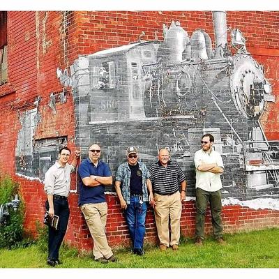The Barrel factory owners in front of a brick wall mural
