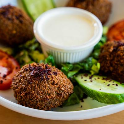 Falafel served with cucumber, tomato, greens, and a sauce for dipping.