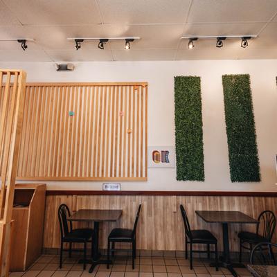Interior with tables, chairs, wooden slats, and green wall panels.