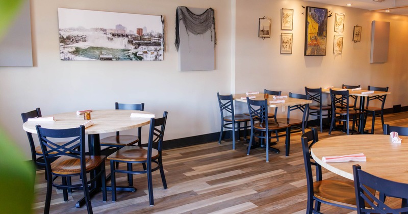 Interior,  wooden tables, black chairs, and framed art on the walls