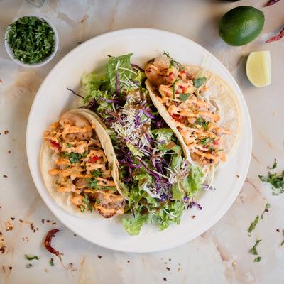 Shrimp tacos served with a salad and limes.