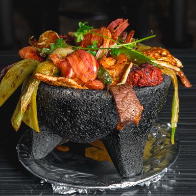 Mixed molcajete with grilled meats, shrimp, and vegetables.