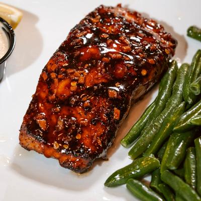 Glazed salmon fillet served with green beans, close-up.