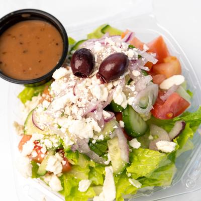 Side salad of lettuce, vegetables, feta and olives, served with a dressing dip